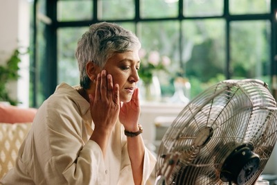 menopausal woman with hot flash in front of fan